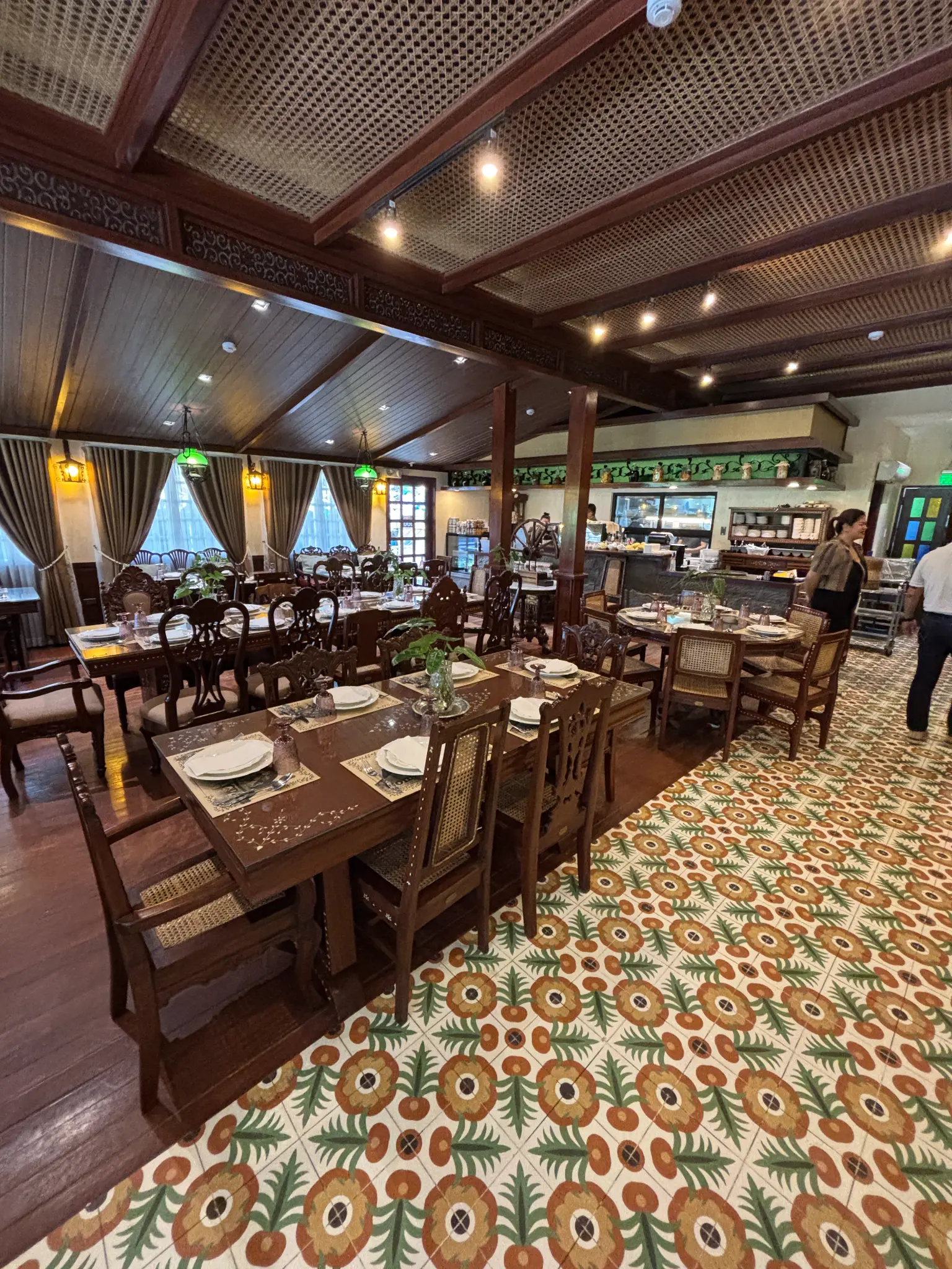 Consuelo’s dining room combines carved wood, woven details, chandeliers, and patterned tiles.