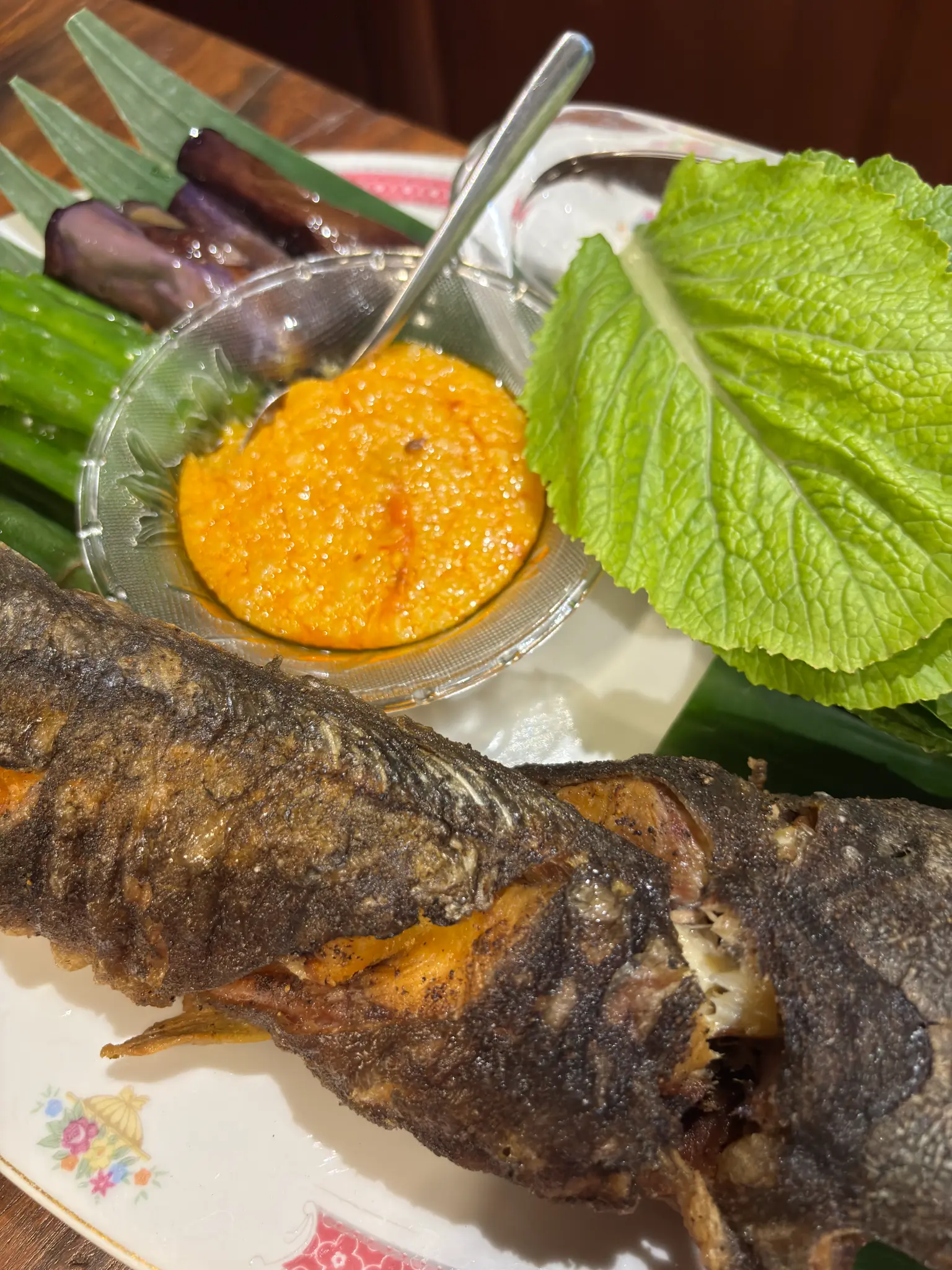 Pritung Hitu is served whole with vegetables, leafy greens, a bright condiment, and burung paro.
