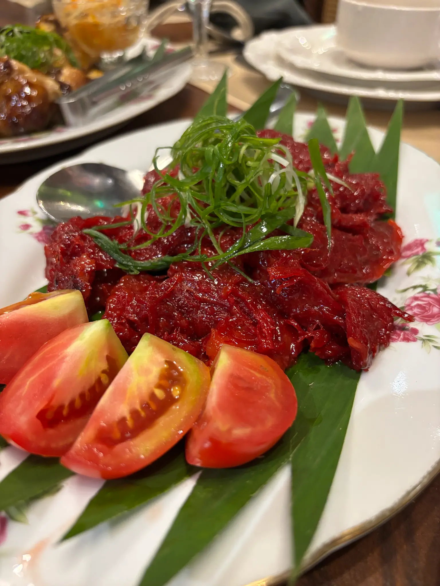 Pindang Damulag arrives in a striking deep-red presentation with fresh herbs and tomatoes.